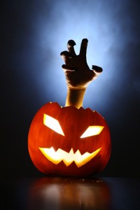 Hand of horror raising from glowing pupmkin lantern.